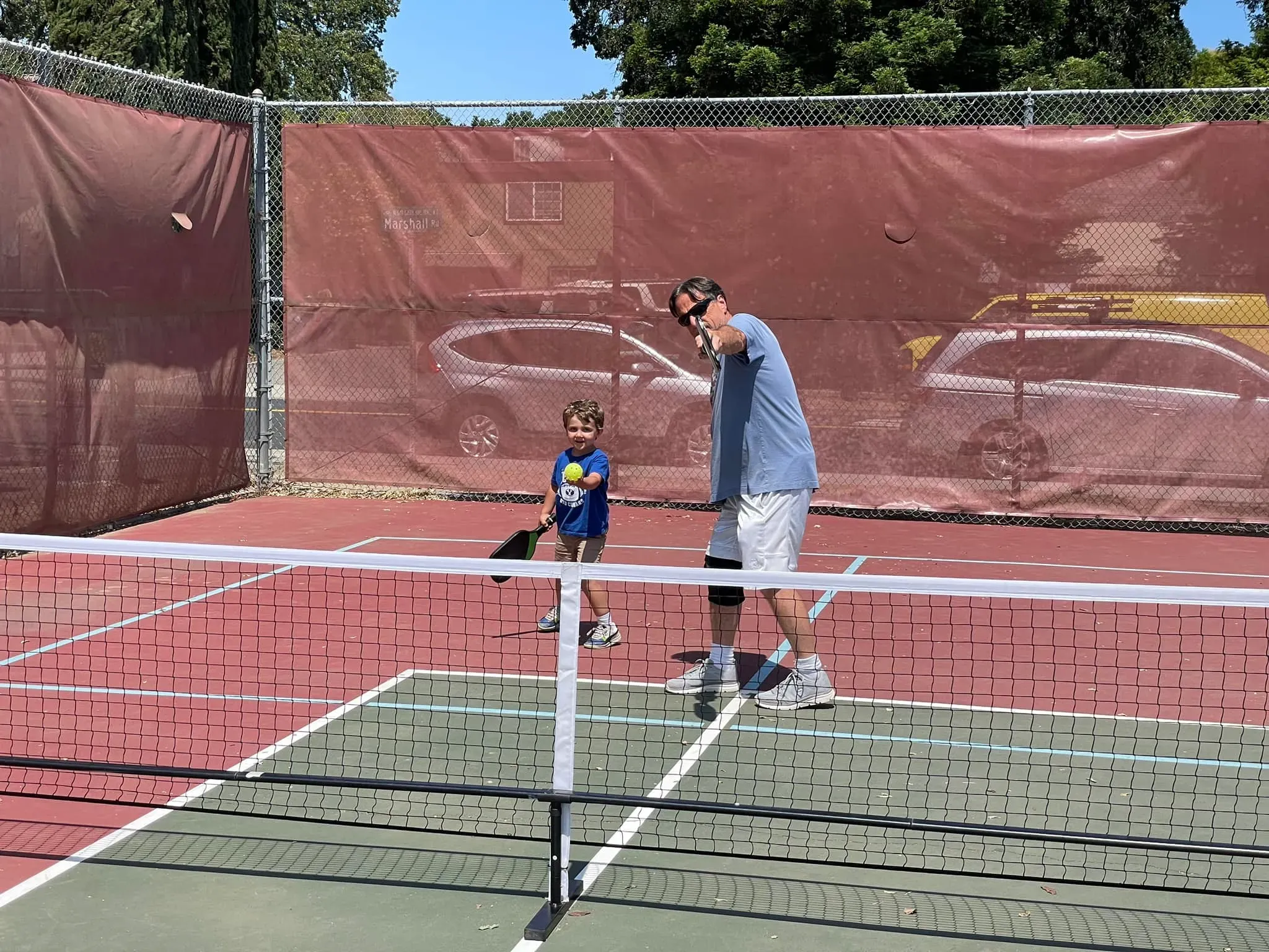 A senior and kid playing pickleball