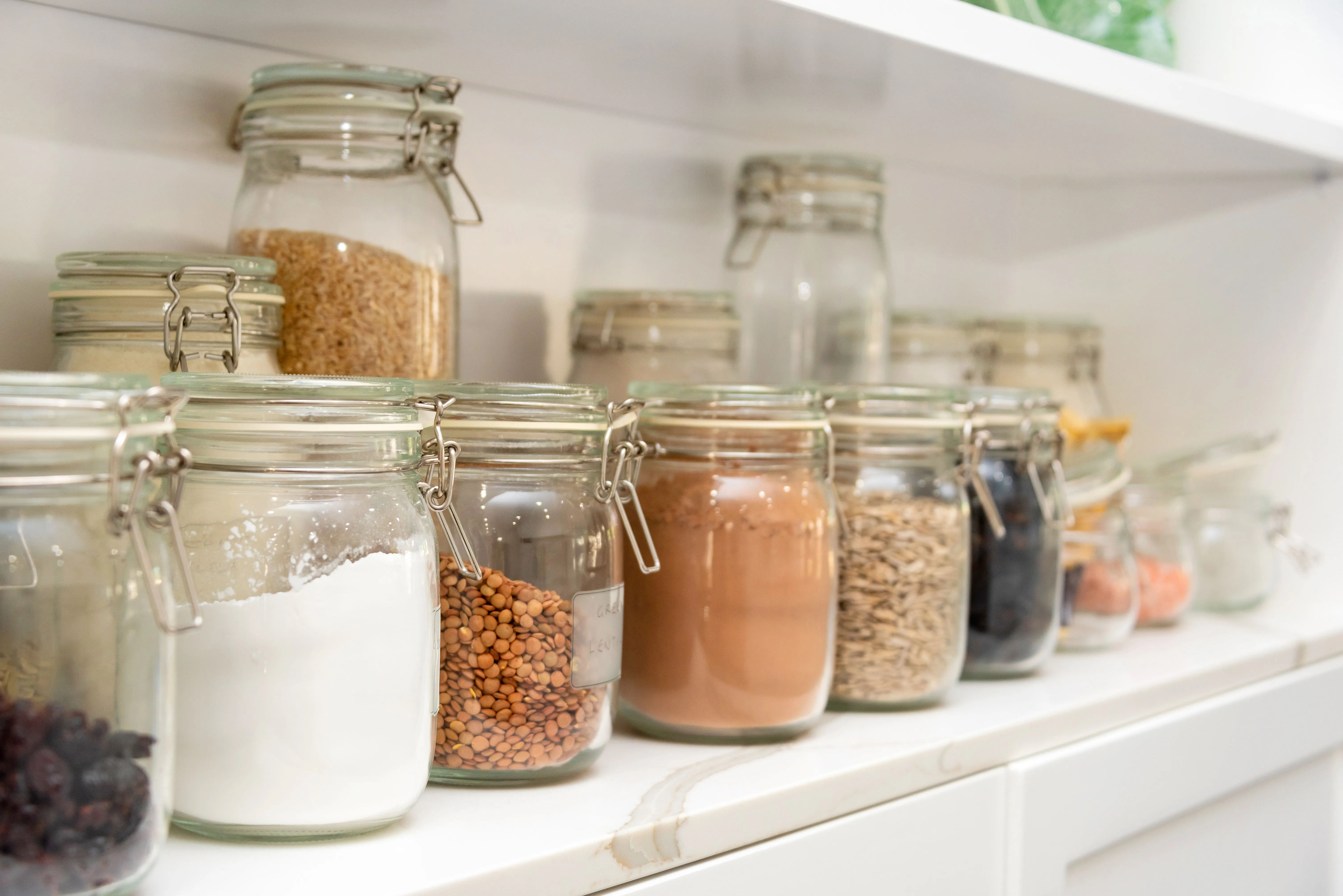 Beans and lentils decanted in mason jars on a shelf.