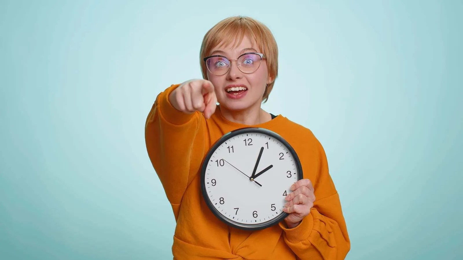 una-psicologa-sosteniendo-un-reloj-en-una-mano-y-señalando-con-la-otra-a-la-camara