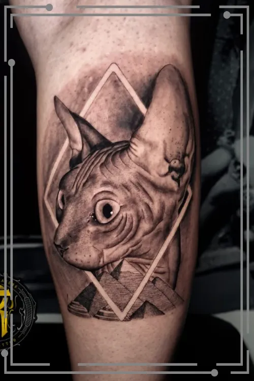 Imagen tatuaje de realismo deun felino sujetando en la boca la cara de una mujer