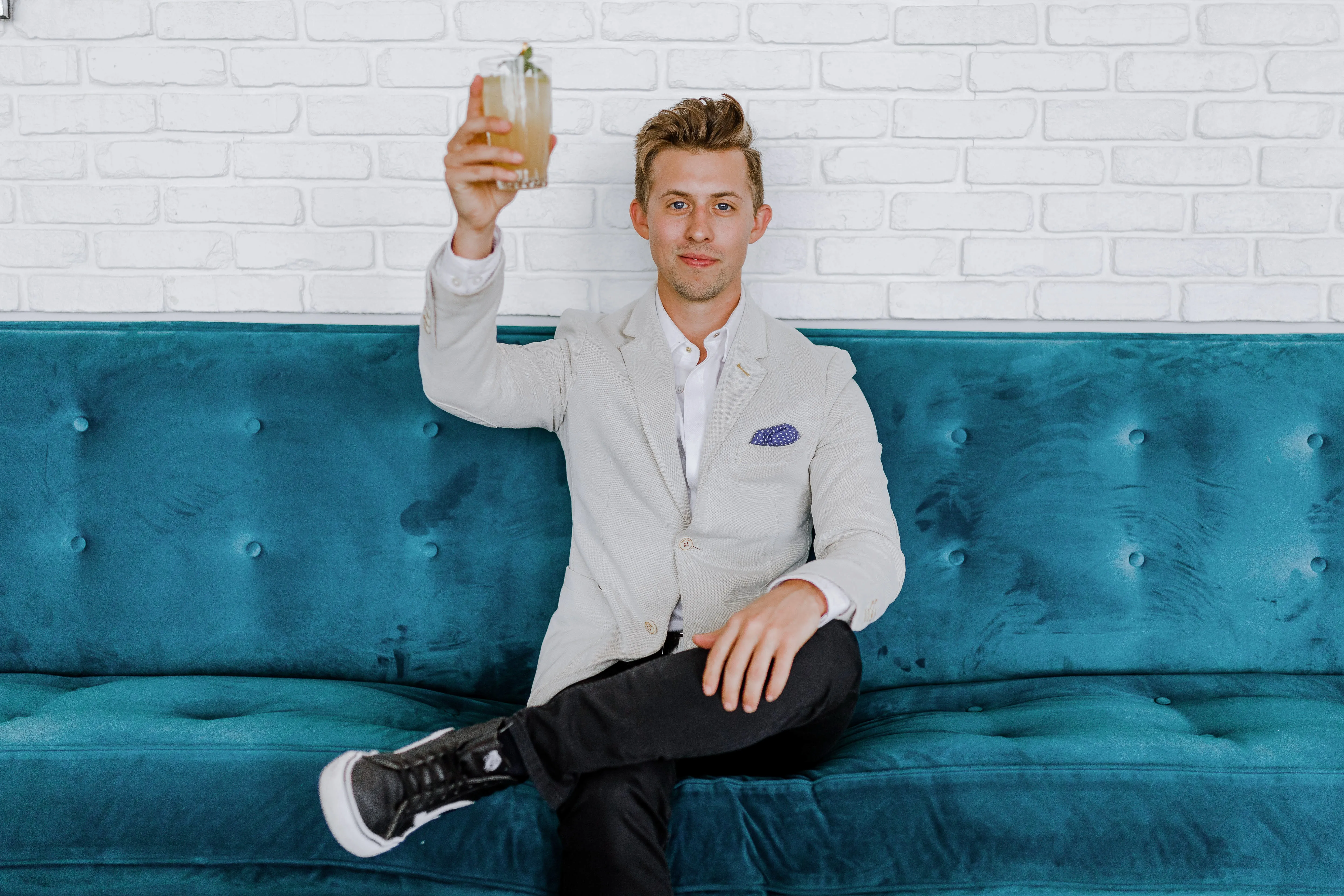 man sitting on a couch raising a glass